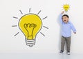 Child student thinking and light bulb on the white wall . Cute little boy has an new idea. Innovation technology and education con Royalty Free Stock Photo