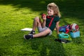 Child study in summer park. Cute little boy with school supplies sitting in elementary school park, eat apple. Early