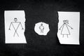 Child suffers from a divorce. Torn sheet of paper with drawn man, woman and child on black background top view copy