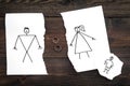 Child suffers from a divorce. Torn sheet of paper with drawn man, woman and child, wedding rings between parts on dark