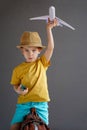 A child in summer clothes and sunglasses sits on a suitcase and holds a toy airplane in his hands. Waiting for travel Royalty Free Stock Photo