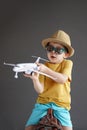 A child in summer clothes and sunglasses sits on a suitcase and holds a toy airplane in his hands. Waiting for travel Royalty Free Stock Photo