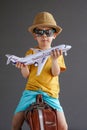 A child in summer clothes and sunglasses sits on a suitcase and holds a toy airplane in his hands. Waiting for travel Royalty Free Stock Photo