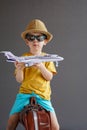 A child in summer clothes and sunglasses sits on a suitcase and holds a toy airplane in his hands. Waiting for travel Royalty Free Stock Photo