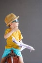 A child in summer clothes and sunglasses sits on a suitcase and holds a toy airplane in his hands. Waiting for travel Royalty Free Stock Photo