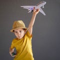 A child in summer clothes and sunglasses sits on a suitcase and holds a toy airplane in his hands. Waiting for travel Royalty Free Stock Photo