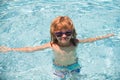 Child in summer swimming pool. Cute boy in the water playing with water. Smiling cute little boy in sunglasses in pool Royalty Free Stock Photo