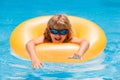 Child in sunglasses floating in pool. Little kid boy floating in a swimming pool on summer vacation. Happy kid playing Royalty Free Stock Photo