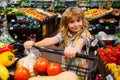 Child in supermarket buying fruit. Kid grocery shopping. Kid with cart choosing fresh vegetables in local store. Healthy Royalty Free Stock Photo