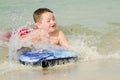 Child surfing on bodyboard at beach Royalty Free Stock Photo