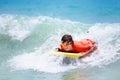 Child surfing on tropical beach. Surfer in ocean. Royalty Free Stock Photo