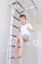 A child on the Swedish wall plays sports at home, a boy climbs a ladder with a rope, the concept of sports and health