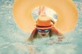 Child in swimming pool on inflatable ring. Kid swim with orange float. Water toy, healthy outdoor sport activity for Royalty Free Stock Photo