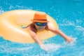 Child in swimming pool on inflatable ring. Kid swim with orange float. Water toy, healthy outdoor sport activity for Royalty Free Stock Photo