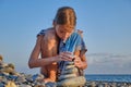 A child in a swimming suit on the seashore is playing with pebbles and building a tower of stones. Royalty Free Stock Photo