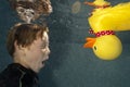 Child swimming underwater withi toy duck
