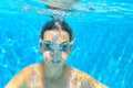 Child swims in pool underwater, funny happy girl in goggles has fun under water and makes bubbles, kid sport Royalty Free Stock Photo