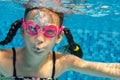 Child swims in pool underwater, funny happy girl in goggles has fun under water and makes bubbles, kid sport Royalty Free Stock Photo