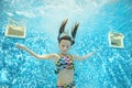 Child swims in pool underwater, happy active girl dives and has fun under water, kid sport Royalty Free Stock Photo