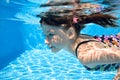 Child swims in swimming pool underwater, happy active girl dives and has fun under water, kid fitness and sport on family vacation