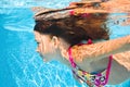 Child swims underwater in swimming pool, active little girl dives and has fun under water, kid fitness and sport Royalty Free Stock Photo