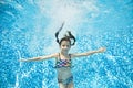 Child swims underwater in swimming pool, active little girl jumps, dives and has fun under water, kid fitness and sport Royalty Free Stock Photo