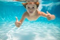 Child swims underwater in swimming pool, happy active boy dives and has fun under water, kids watersport. Children play