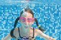 Child swims underwater in swimming pool, happy active girl in goggles dives and has fun under water, kid fitness and sport Royalty Free Stock Photo