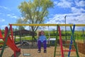 Child swinging on playground on sunny summer day in a playground. Kids swing. School or kindergarten yard and play