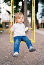 Child swinging on a yellow swing in the playground Royalty Free Stock Photo