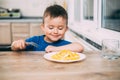 A child in a t-shirt in the kitchen eating an omelet, a fork Royalty Free Stock Photo