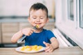 A child in a t-shirt in the kitchen eating an omelet, a fork Royalty Free Stock Photo