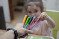 Bright multi-colored colors. A child takes a felt-tip pen from the hands of a teacher.