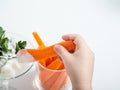 the child takes a glass of sliced fresh carrots. the concept of healthy eating for children and adults.