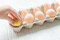 The child takes out a golden egg from the egg tray. A dozen chicken eggs on the table. Rise in price of products in