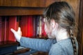 The child takes the red book from the bookshelf. View from the back. Little girl pulls out a textbook for reading. Selective focus Royalty Free Stock Photo