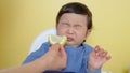 A child tastes a piece of lemon, wrinkles and makes a grimace