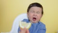 A child tastes a piece of lemon, wrinkles and makes a grimace