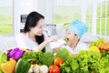 Child tasting salad with his mother