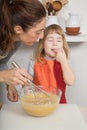 Child tasting whipped cream next to mother