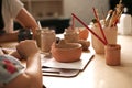 A child with a teacher at a pottery master class. the teacher teaches the child to paint on ceramics.