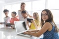 Child with technology tablet and laptop computer in classroom teacher on the background Royalty Free Stock Photo