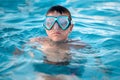 A child, a teenager in a swimming mask swims in clear blue water in a pool, pond or ocean, close-up
