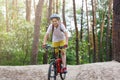 Child teenager in white t shirt and yellow shorts on bicycle ride in forest at spring or summer. Happy smiling Boy cycling