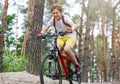 Child teenager in white t shirt and yellow shorts on bicycle ride in forest at spring or summer. Happy smiling Boy cycling