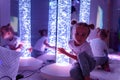 Child in therapy sensory stimulating room, snoezelen. Autistic child interacting with colored bubble tube lamp during therapy. Royalty Free Stock Photo