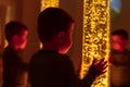 Child in therapy sensory stimulating room, snoezelen. Child interacting with colored lights bubble tube lamp during therapy.