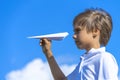 Child throwing white paper plane. Boy playing with paper airplane against blue sky on sunny day outdoors Royalty Free Stock Photo
