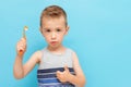 Child thumb up with manual toothbrush isolated on a blue background
