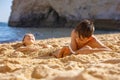 Child, tickling sibling on the beach on the feet with feather, kid cover in sand, smiling, laughing